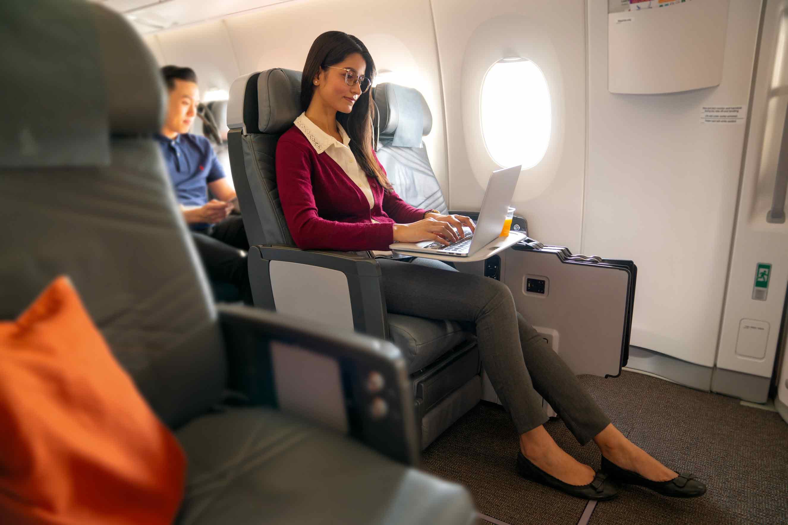 Frau mit Getränk und Kopfhörer in Singapore Airlines